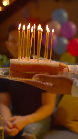 Vertical-Video-Close-Up-Of-Woman-Holding-Birthday-Cake-Decorated-With-Lit-Candles-At-Party-At-Home